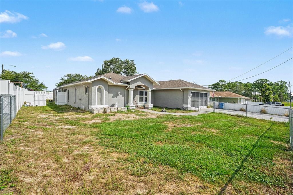 A single-story house with a gray stucco exterior and a large, grassy side yard — 4187 EVERETT AVENUE, SPRING HILL, FL