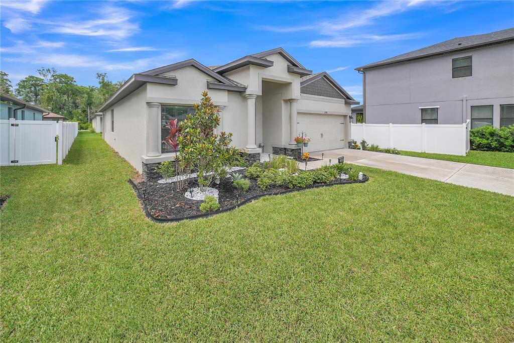 A single-story house with a beige stucco exterior, a two-car garage, and a landscaped yard — 12591 VANDER WAY, NEW PORT RICHEY, FL