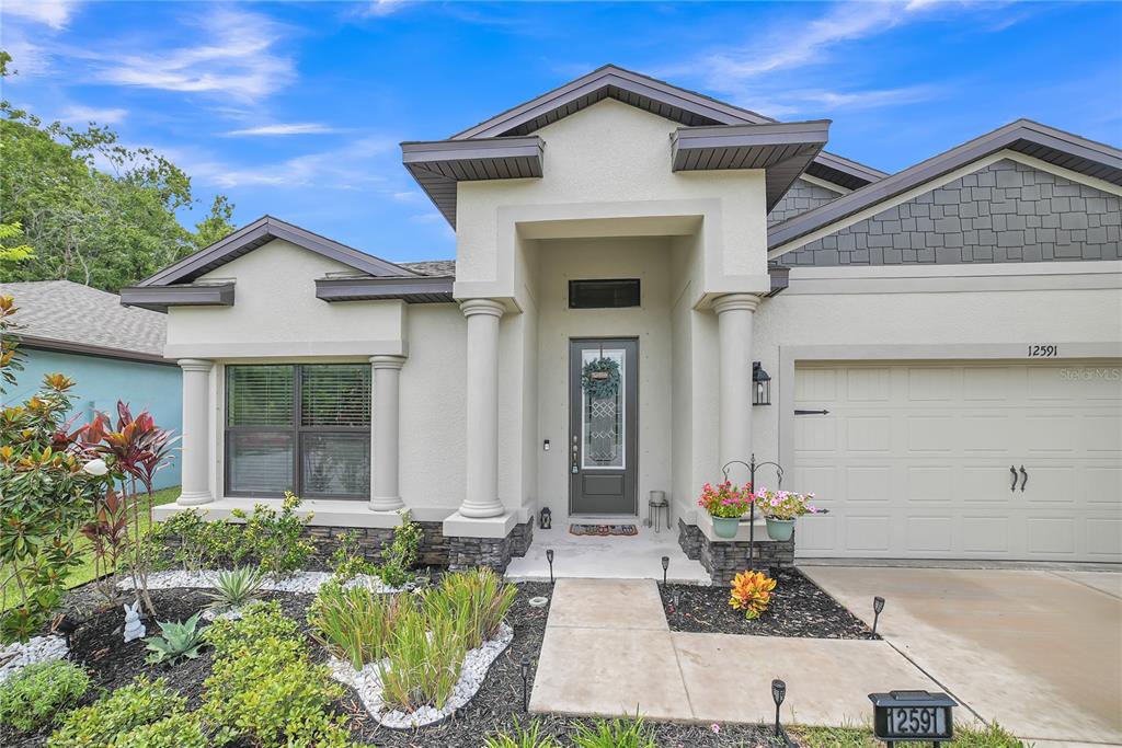 A single-story house with a stucco exterior, stone accents, and a front-facing garage — 12591 VANDER WAY, NEW PORT RICHEY, FL
