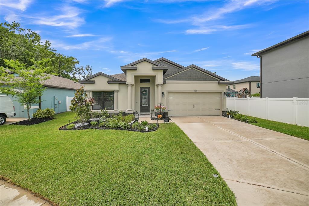 A single-story house with a beige stucco exterior, a two-car garage, and a front lawn — 12591 VANDER WAY, NEW PORT RICHEY, FL