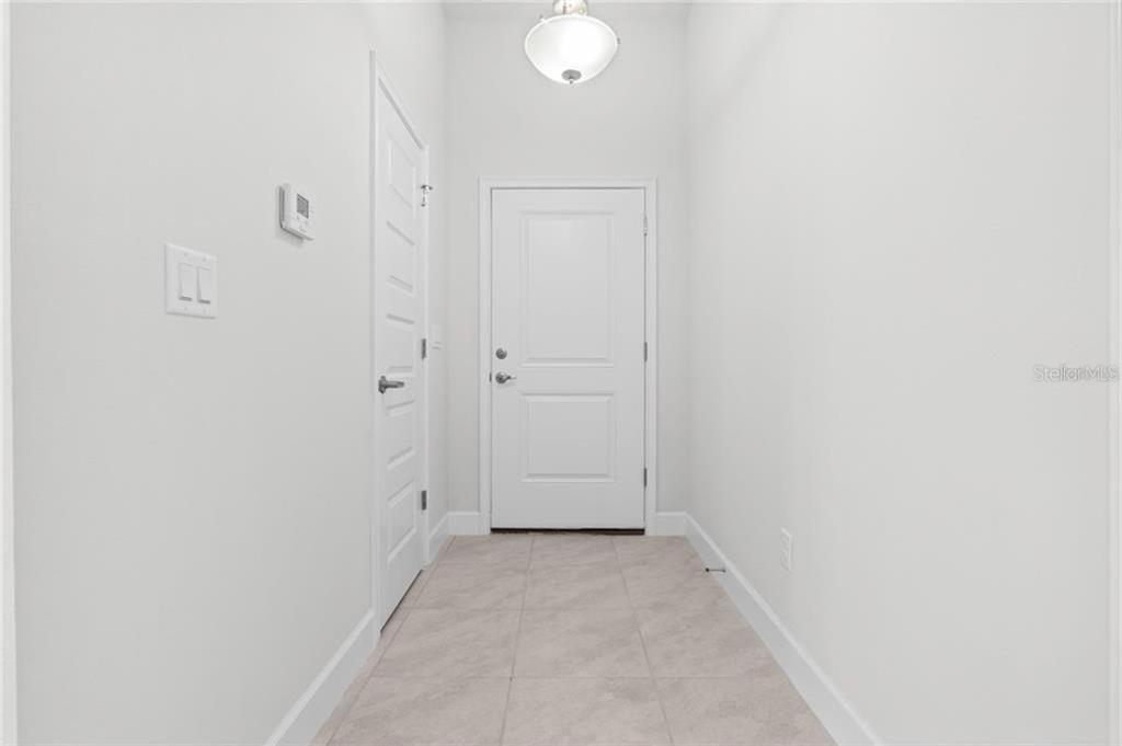A bright entryway features white walls, a tiled floor, and a white front door — 15 BIRCHWOOD DRIVE, PALM COAST, FL