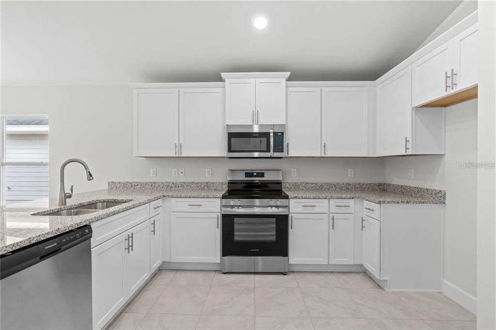 A kitchen features white cabinets, stainless steel appliances, and granite countertops — 15 BIRCHWOOD DRIVE, PALM COAST, FL