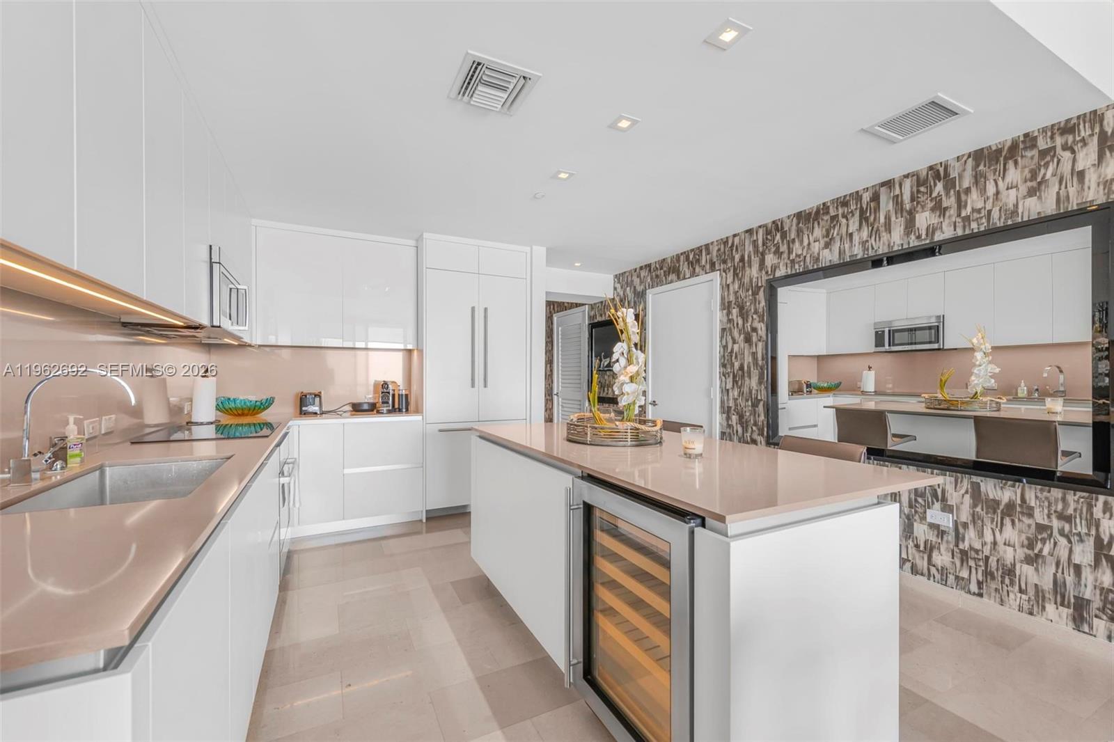 A modern kitchen features white cabinetry, a central island with a wine cooler, and countertops — 88 SW 7th St # 3806, Miami FL 33130, MIAMI, FL