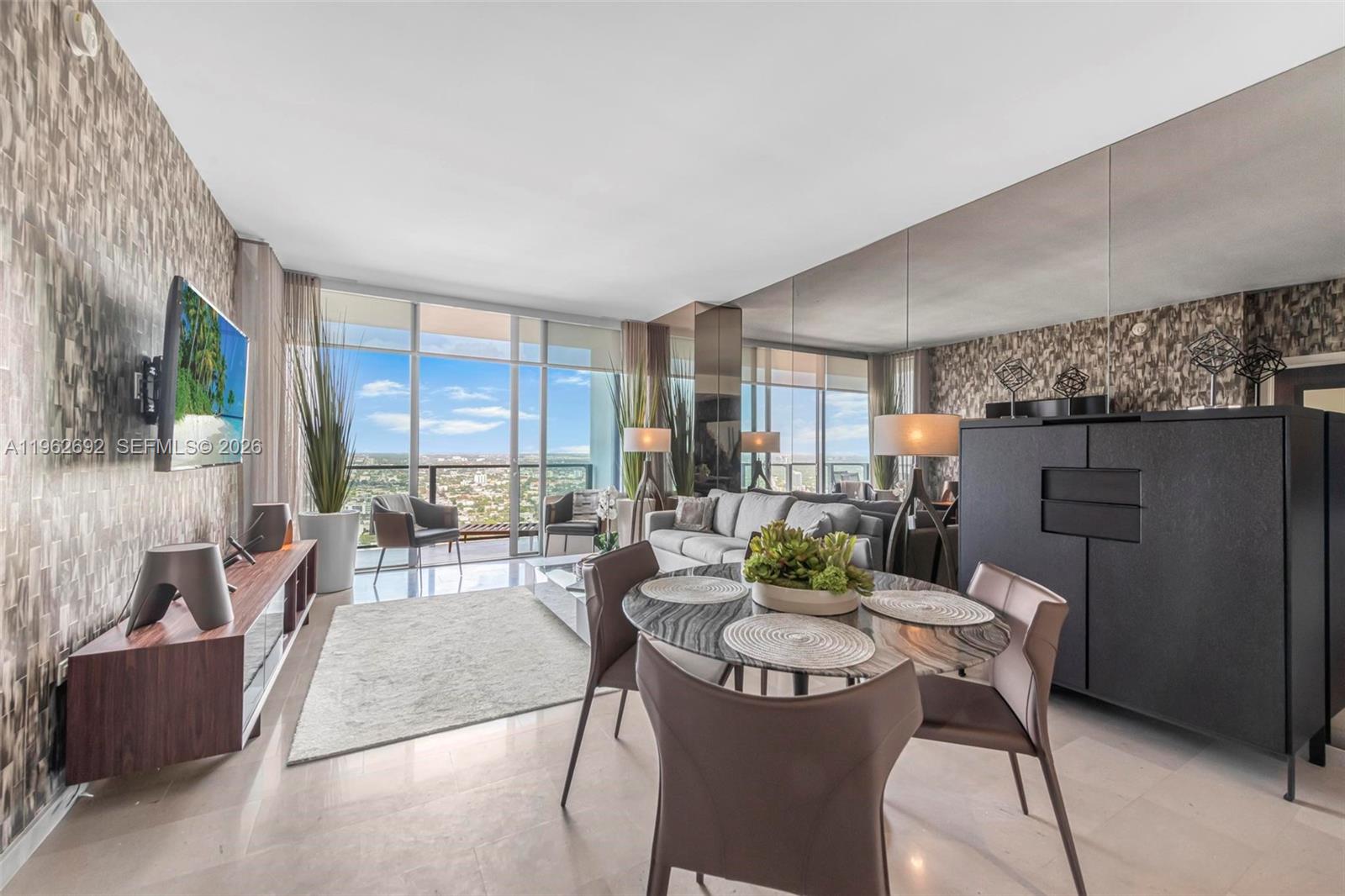 A modern living and dining area features floor-to-ceiling windows with a city view — 88 SW 7th St # 3806, Miami FL 33130, MIAMI, FL