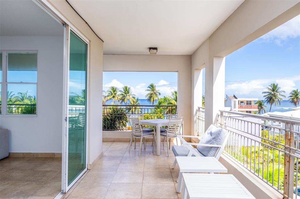 A covered balcony with tile flooring, outdoor dining furniture, and a view of the ocean — PR-115 MAR AZUL CONDOMINIUM UNIT 2BN, AGUADA, PR