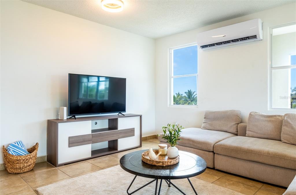 A living room features a television on a media console, a sofa, and tile flooring — PR-115 MAR AZUL CONDOMINIUM UNIT 2BN, AGUADA, PR