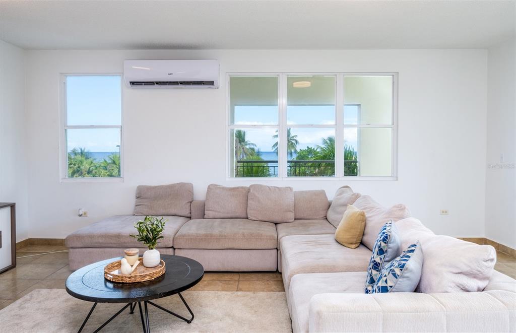 A living room features a large sectional sofa, a round coffee table, and ocean views — PR-115 MAR AZUL CONDOMINIUM UNIT 2BN, AGUADA, PR
