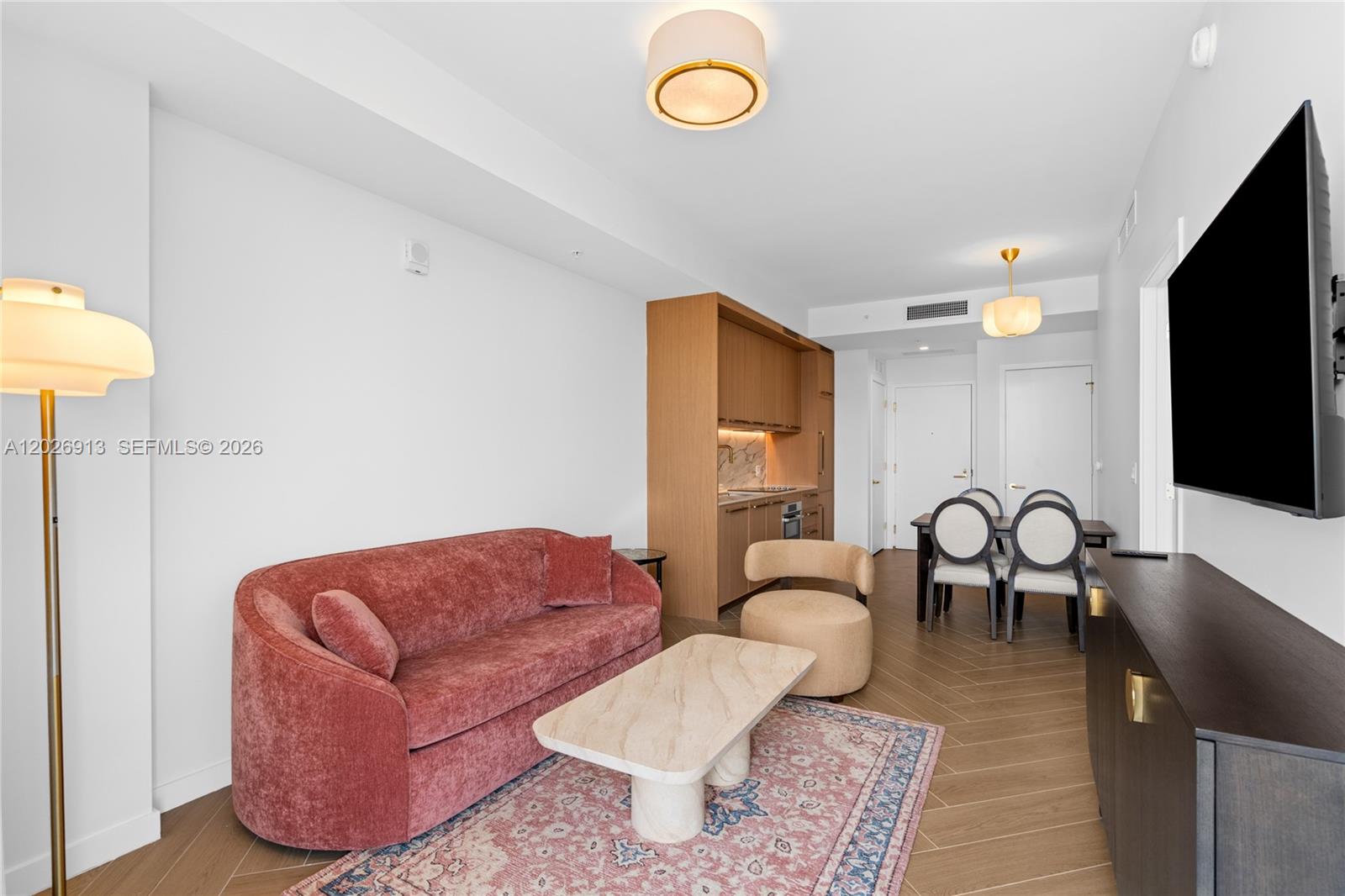 A modern living room features a red sofa, marble coffee table, and an open kitchenette — 2700 NW 2nd Ave # 717, Miami FL 33127, MIAMI, FL