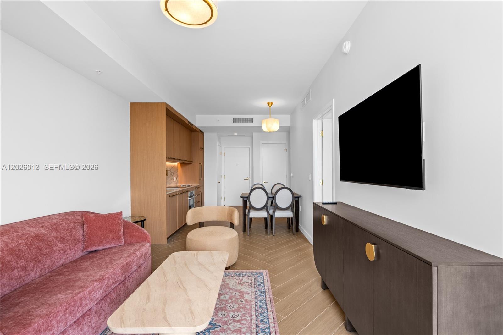 A living room features a pink sofa, a wooden cabinet, and a small dining area — 2700 NW 2nd Ave # 717, Miami FL 33127, MIAMI, FL
