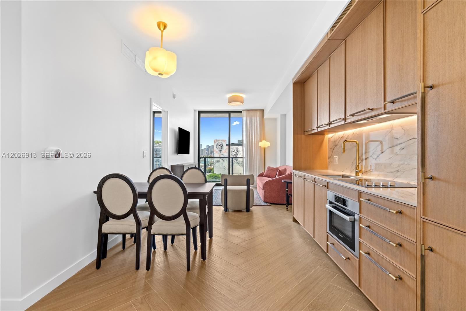 A modern kitchen and dining area feature light wood cabinetry, herringbone flooring, and balcony views — 2700 NW 2nd Ave # 717, Miami FL 33127, MIAMI, FL