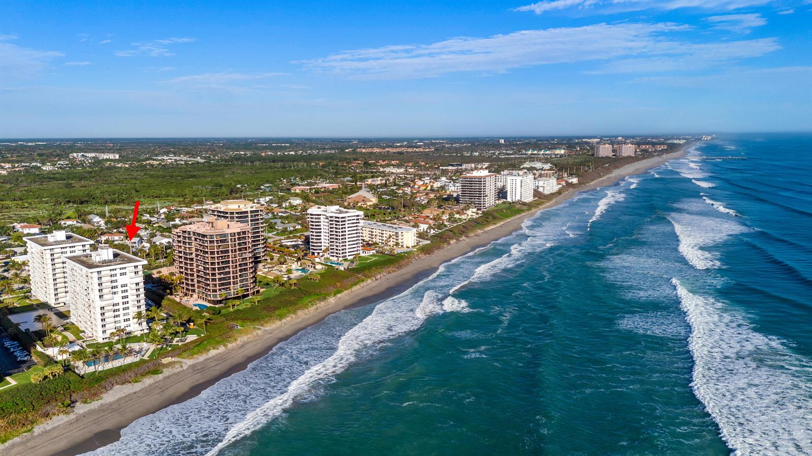 An aerial view shows high-rise condominiums along a sandy beach bordering the ocean — 500 Ocean Drive # 11b, Juno Beach FL 33408, JUNO BEACH, FL