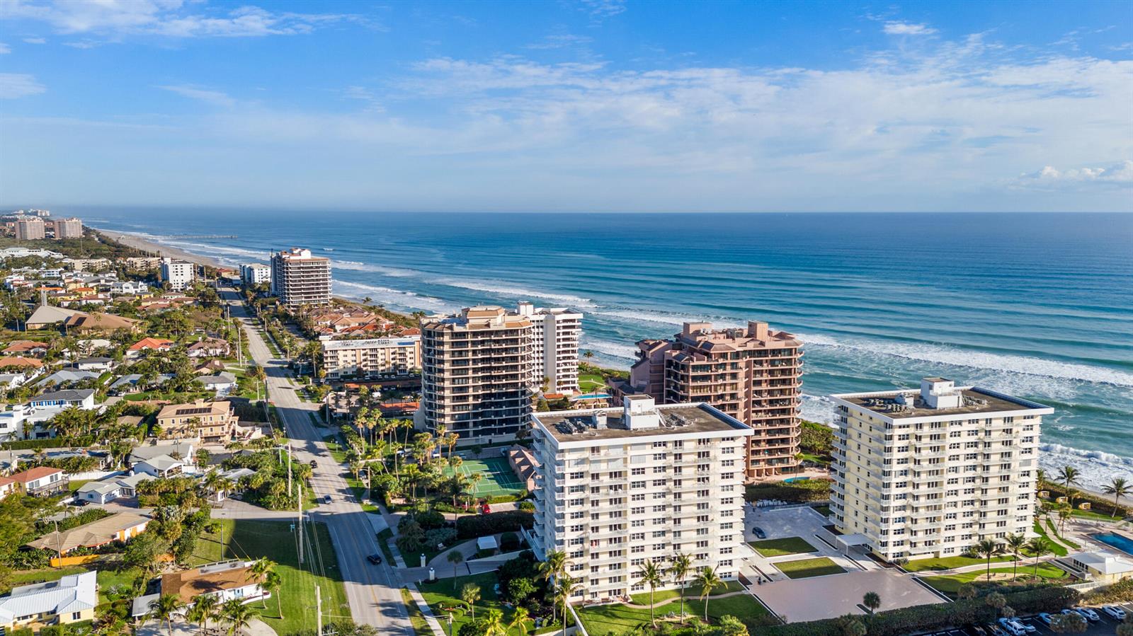 An aerial view shows high-rise apartment buildings situated along a sandy beach and ocean — 500 Ocean Drive # 11b, Juno Beach FL 33408, JUNO BEACH, FL