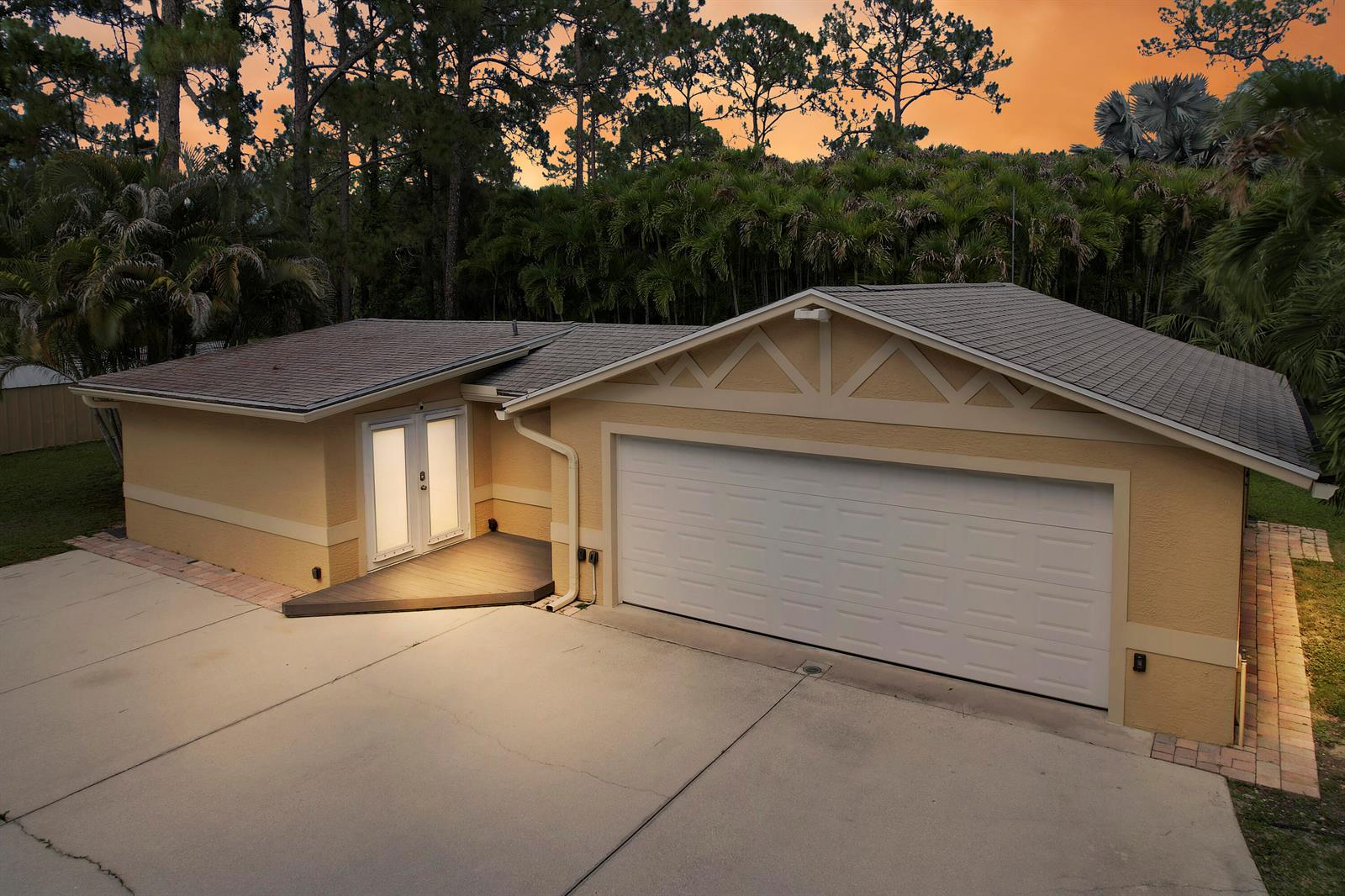 An exterior view of a single-story house with a two-car garage and a front deck — 12263 Sandy Run, Jupiter FL 33478, JUPITER, FL