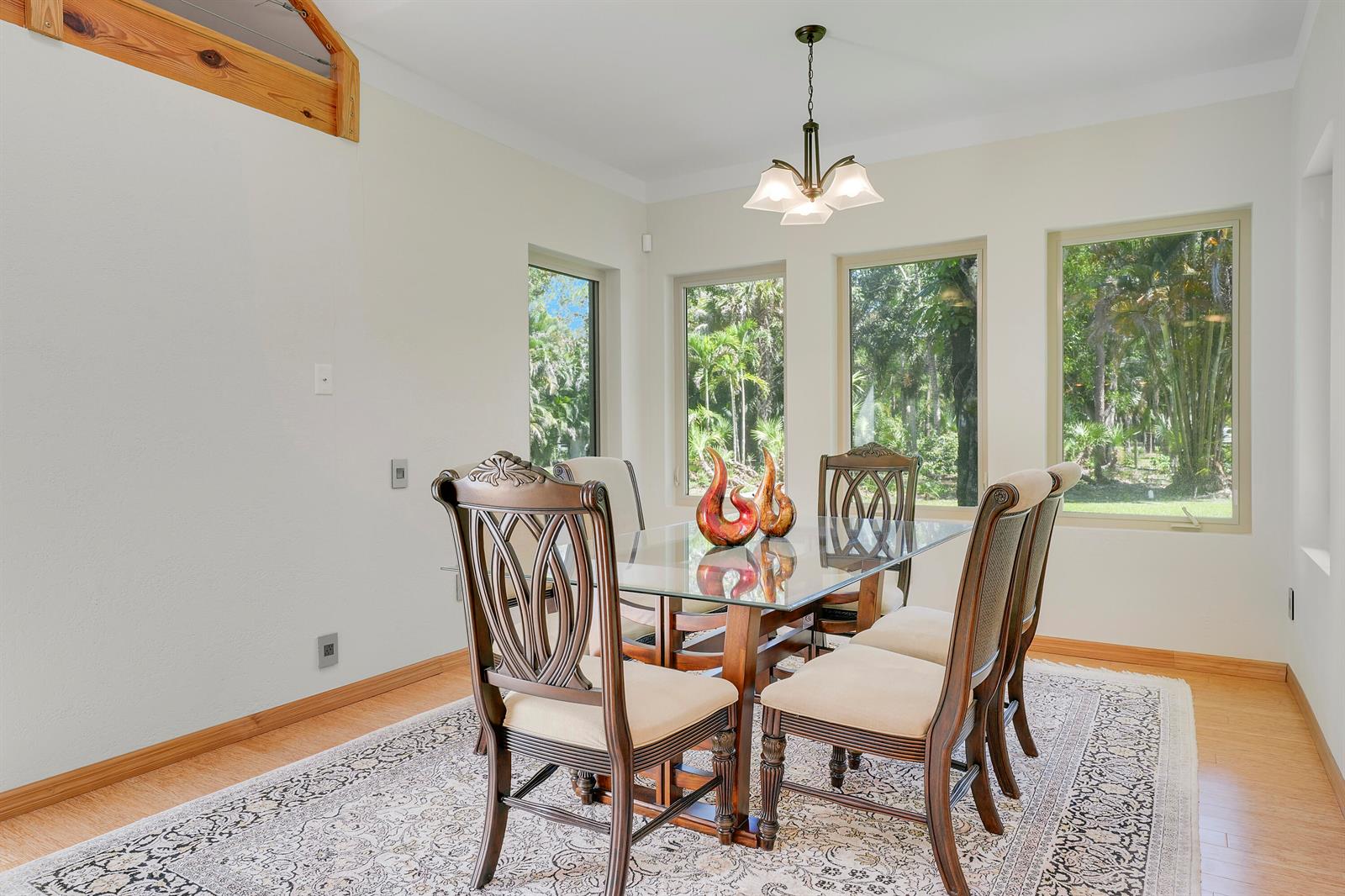 A dining room with a glass-topped table, six chairs, and large windows overlooking trees — 12263 Sandy Run, Jupiter FL 33478, JUPITER, FL