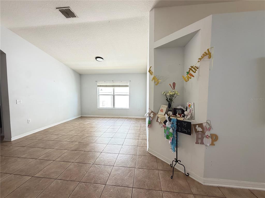 A tiled hallway leads from the entryway toward an open living area with arched openings — 945 TRAMELLS TRAIL, KISSIMMEE, FL