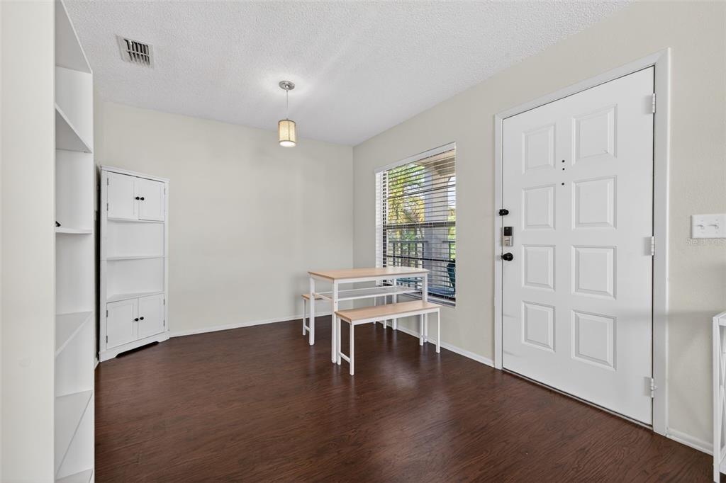 A dining area features dark wood-look flooring, a white cabinet, and a small wooden table — 2597 COUNTRYSIDE BOULEVARD UNIT 209, CLEARWATER, FL