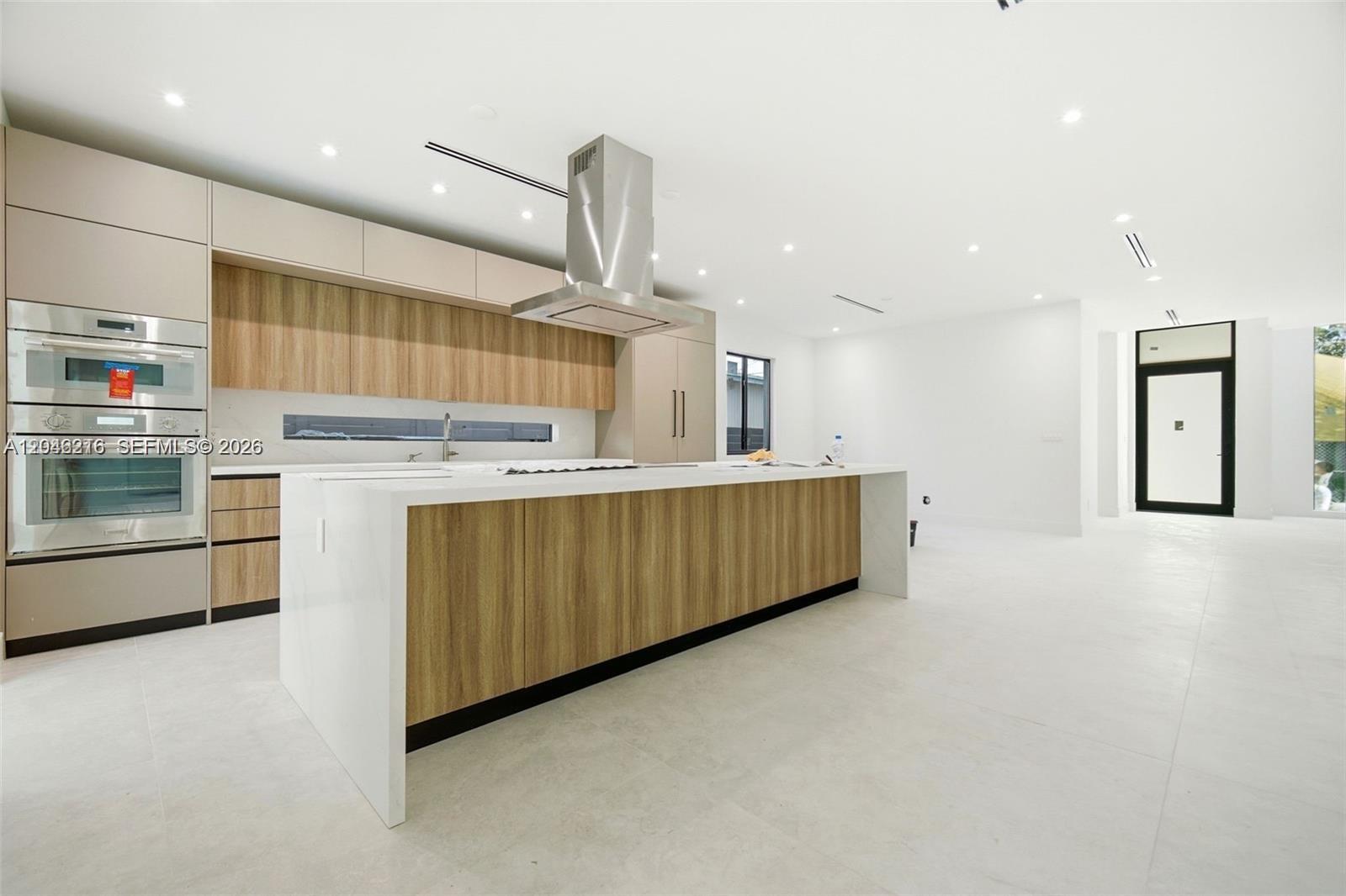 A modern kitchen features a large wood-paneled island, white countertops, and stainless steel appliances — 3545 Florida Ave, Miami FL 33133, MIAMI, FL