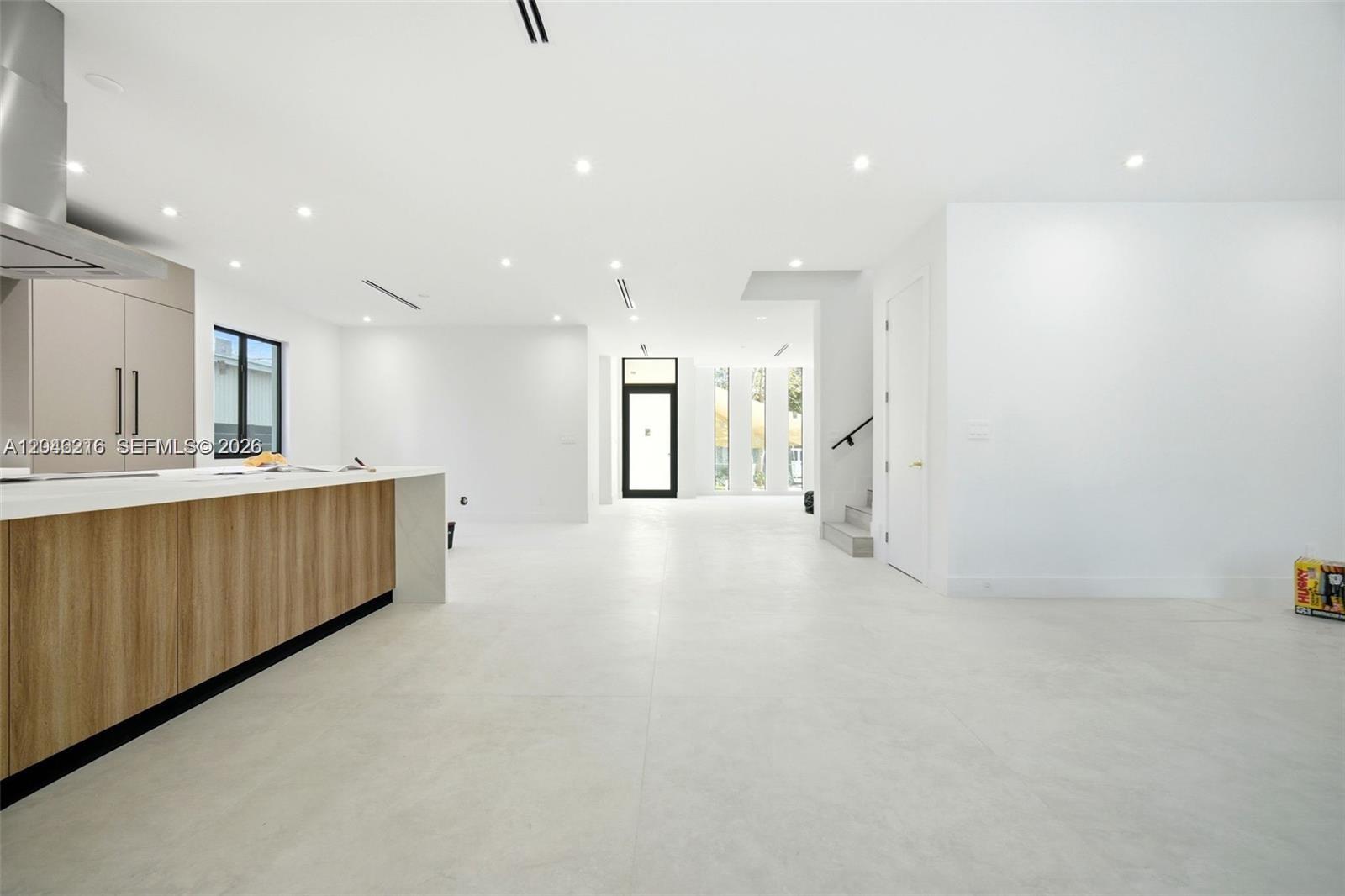 A modern, minimalist kitchen and open living area feature white walls and light tile flooring — 3545 Florida Ave, Miami FL 33133, MIAMI, FL