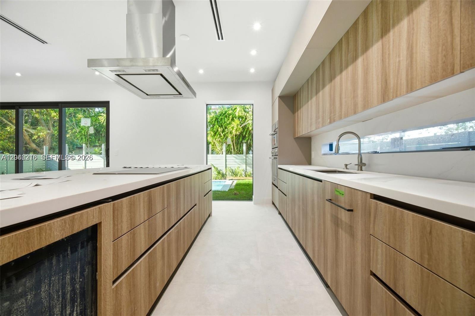 A modern kitchen features wood-grain cabinetry, white countertops, a stainless steel range hood, and windows — 3545 Florida Ave, Miami FL 33133, MIAMI, FL