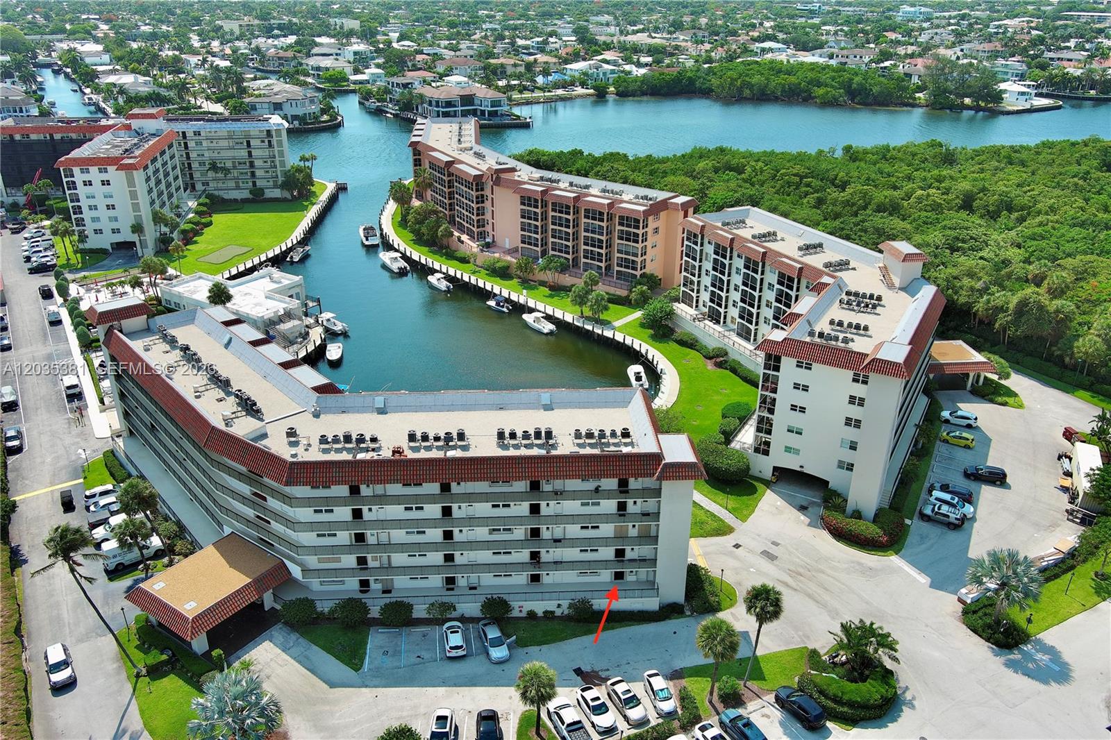 An aerial view shows multi-story apartment buildings surrounding a canal with boat slips — 2871 N Ocean Blvd # M126, Boca Raton FL 33431, BOCA RATON, FL