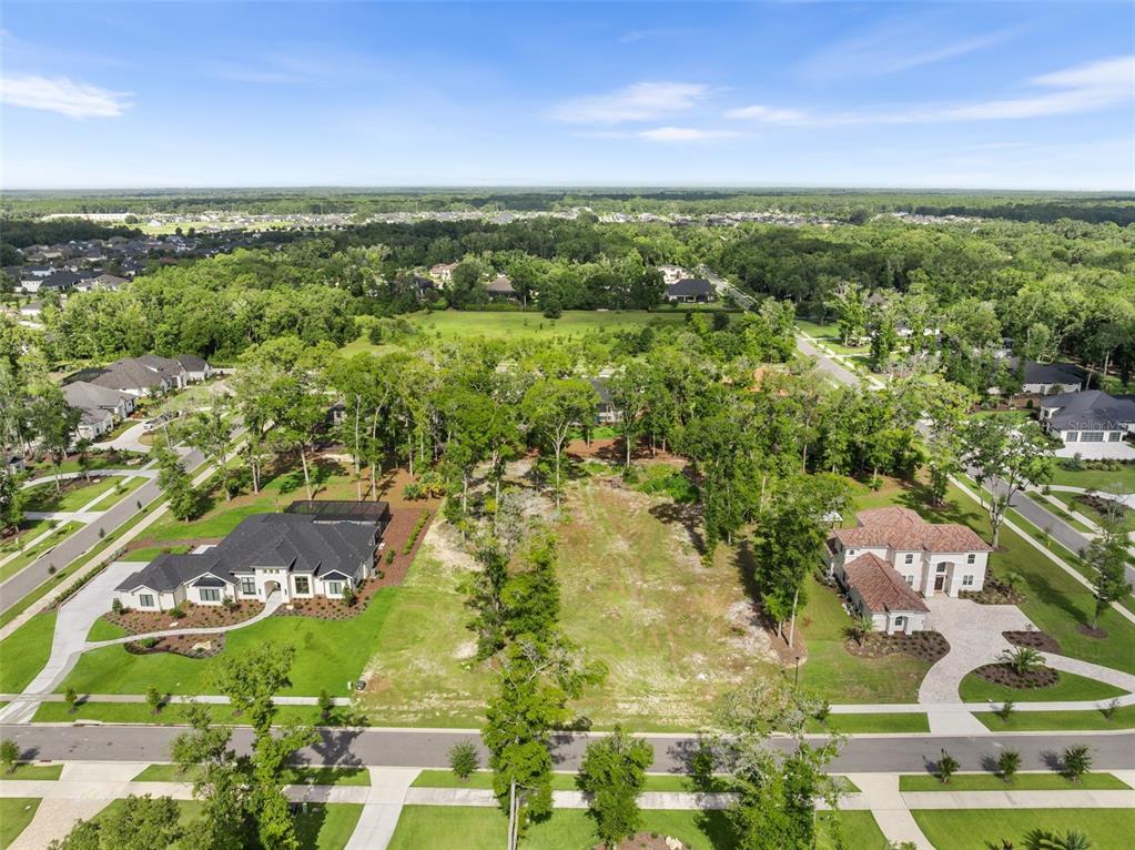An aerial view shows a vacant residential lot situated between two large houses and trees — 3120 SW 108TH WAY, GAINESVILLE, FL