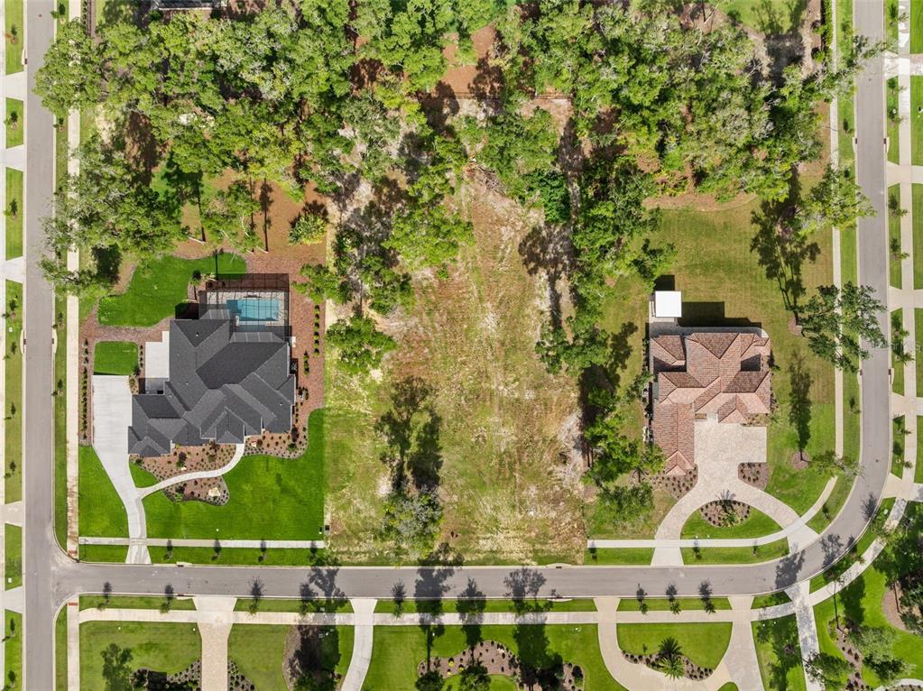An aerial view shows a vacant residential lot situated between two large houses with pools — 3120 SW 108TH WAY, GAINESVILLE, FL