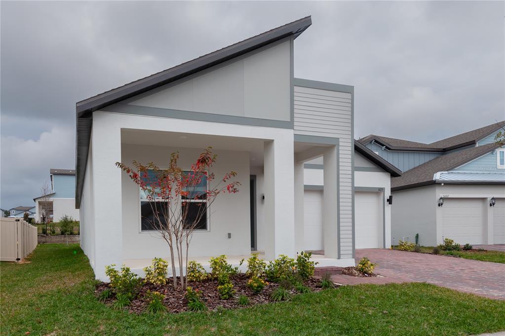 A modern single-story house with a slanted roof, white stucco walls, and a paved driveway — 16271 SILVER GROVE BLVD, WINTER GARDEN, FL