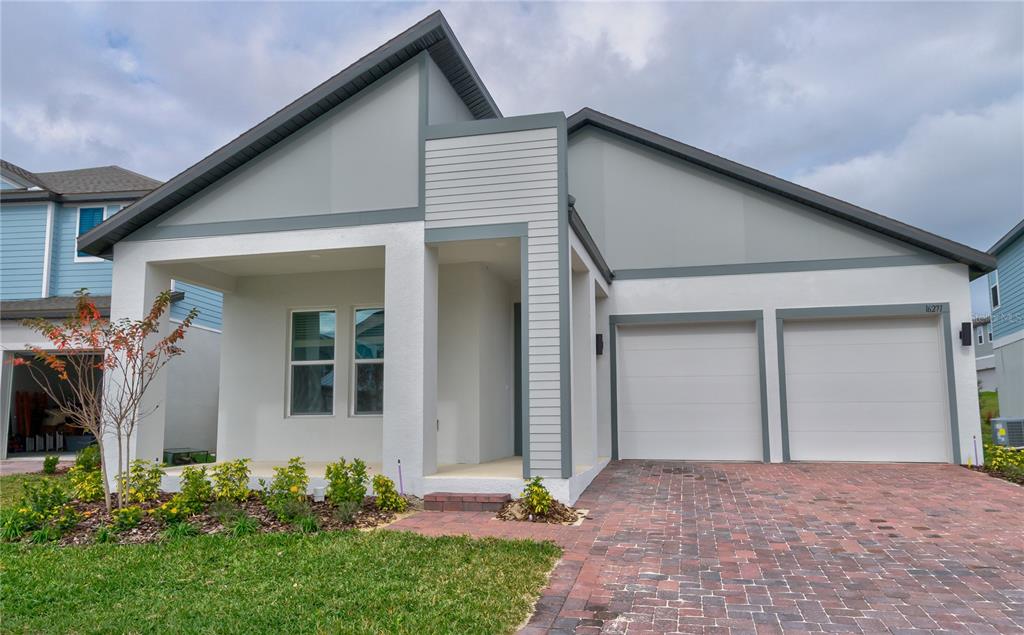 A modern single-story house with a two-car garage, white stucco exterior, and brick paver driveway — 16271 SILVER GROVE BLVD, WINTER GARDEN, FL