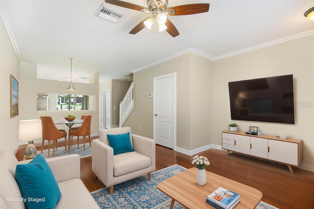 A living room with hardwood floors, a ceiling fan, and a wall-mounted television — 2403 LAKE WOODBERRY CIRCLE, BRANDON, FL