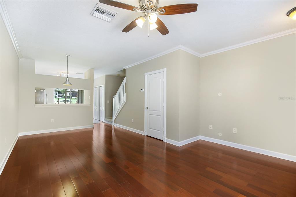 An empty living room with hardwood floors, a ceiling fan, and a staircase — 2403 LAKE WOODBERRY CIRCLE, BRANDON, FL