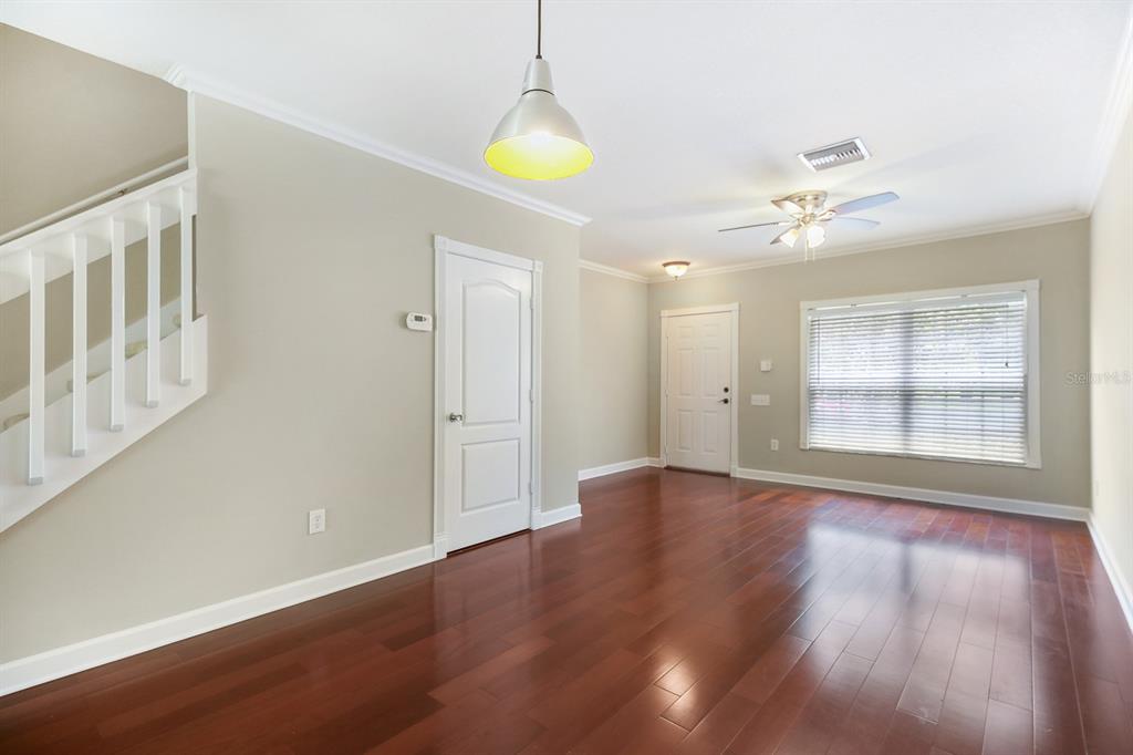 A living room with hardwood floors, a staircase, a ceiling fan, and a front door — 2403 LAKE WOODBERRY CIRCLE, BRANDON, FL