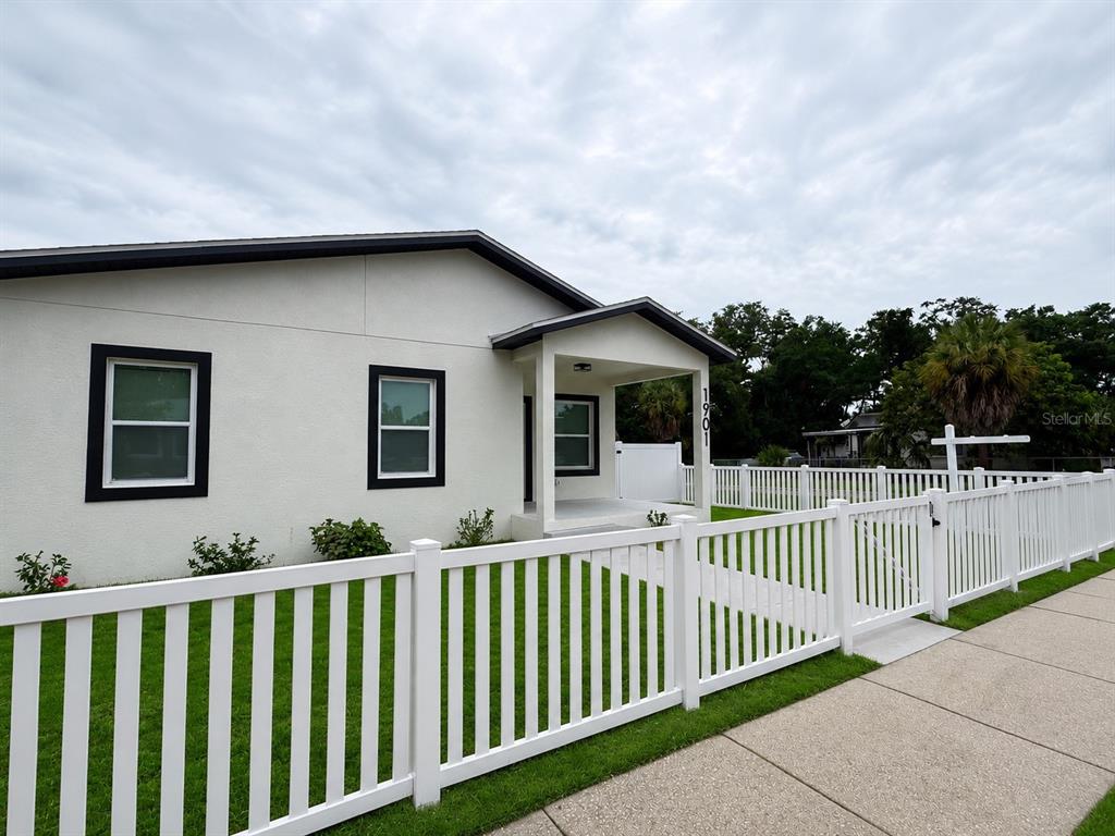 A white house with a covered porch and a white picket fence under a cloudy sky — 1901 31ST STREET S, ST PETERSBURG, FL