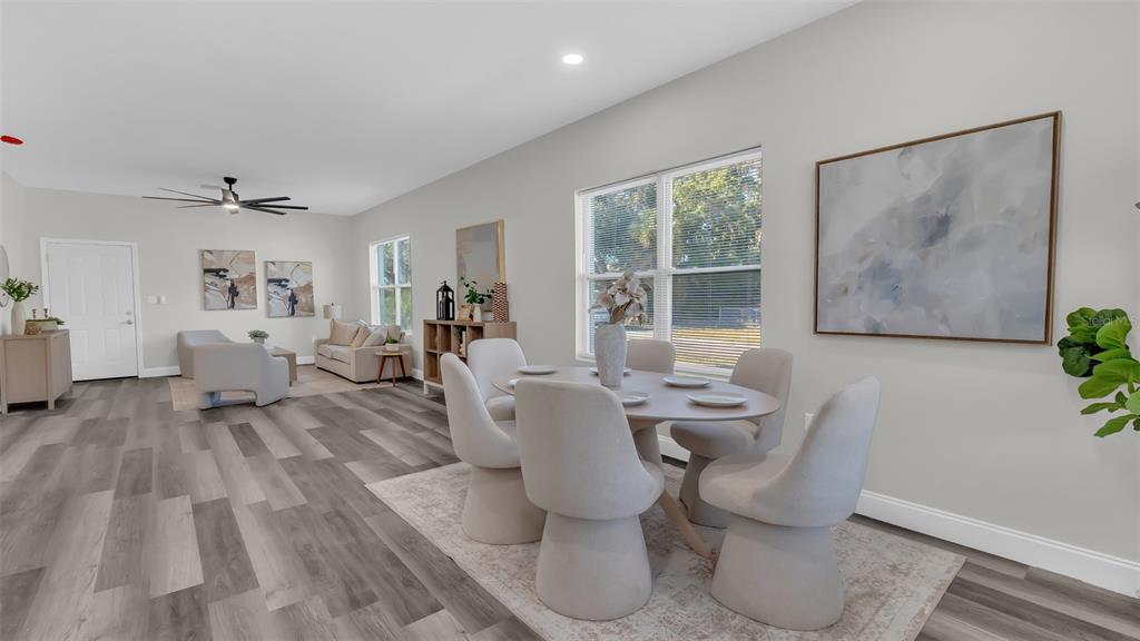 An open-concept dining and living area features light gray walls, wood-look flooring, and modern furniture — 1901 31ST STREET S, ST PETERSBURG, FL