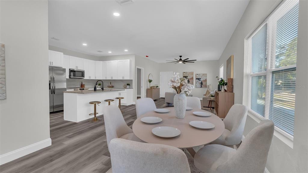 An open-concept kitchen and dining area features white cabinetry, a kitchen island, and gray flooring — 1901 31ST STREET S, ST PETERSBURG, FL