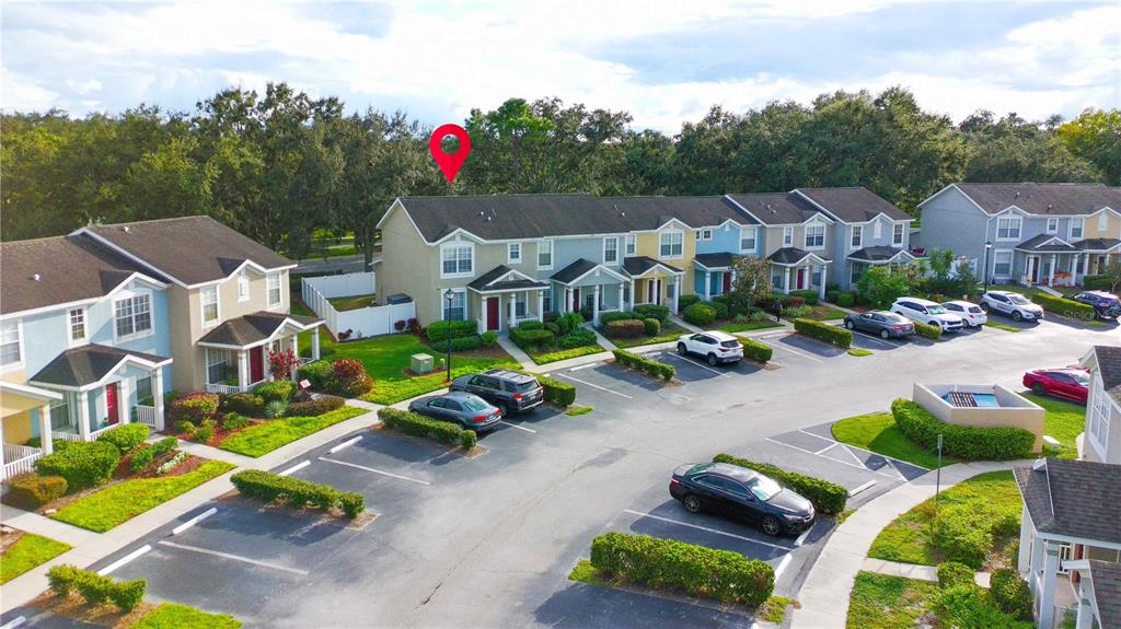 An aerial view shows a row of multi-story townhomes with parking spaces in front — 3314 BROKEN BOW DRIVE, LAND O LAKES, FL
