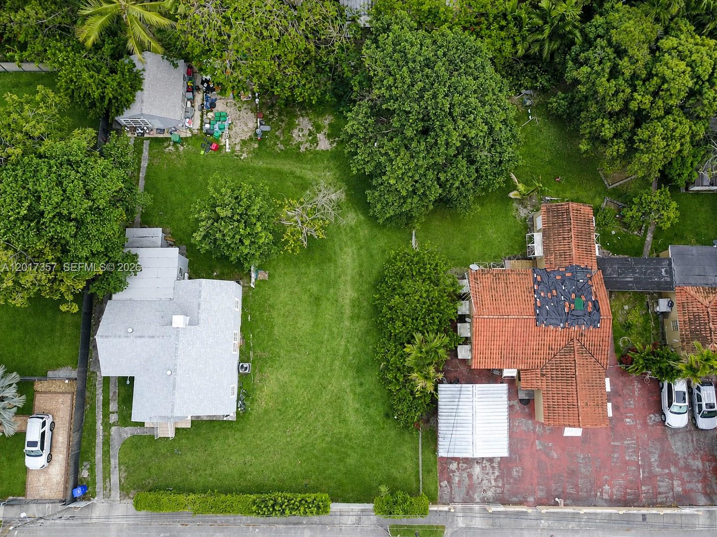 An aerial view shows two houses separated by a large grassy yard with mature trees — 1555 NW 26TH ST, Miami FL 33142, MIAMI, FL