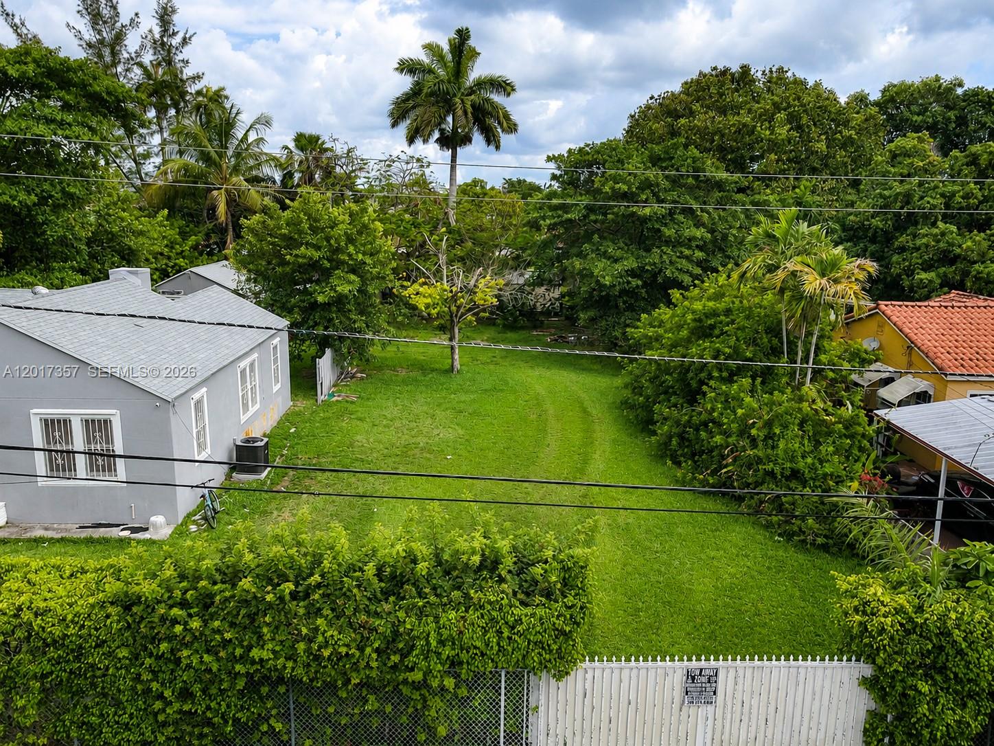 An aerial view shows a grassy backyard between a gray house and a yellow house — 1555 NW 26TH ST, Miami FL 33142, MIAMI, FL