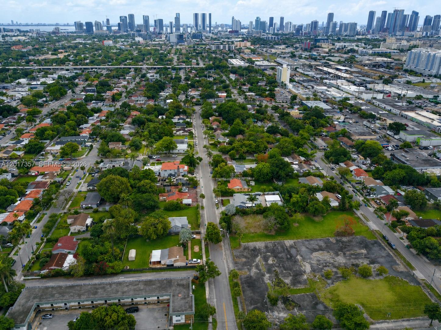 An aerial view shows a residential neighborhood with a city skyline in the background — 1555 NW 26TH ST, Miami FL 33142, MIAMI, FL