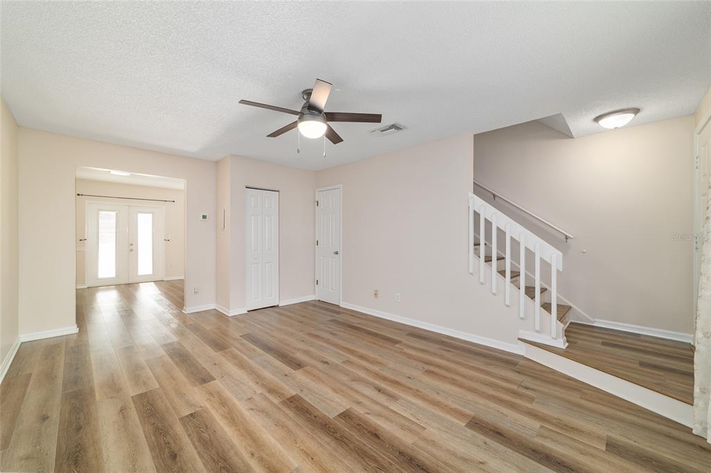 A living room features wood-look flooring, a ceiling fan, and a staircase with white railings — 1701 SE 24TH ROAD UNIT 102, OCALA, FL