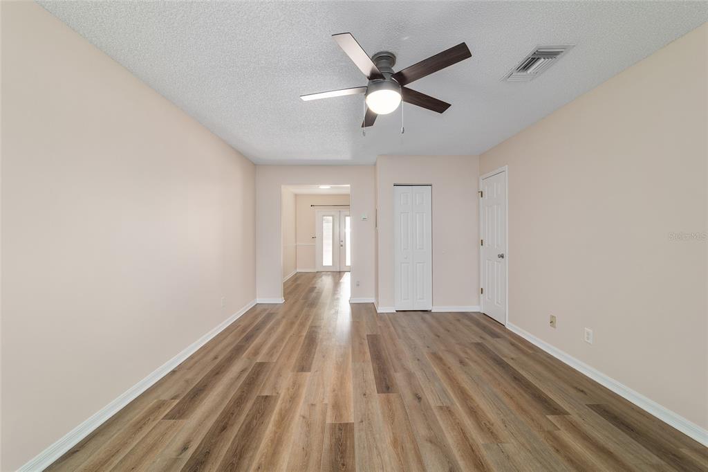 An empty room with wood-look flooring, a ceiling fan, and two closed white doors — 1701 SE 24TH ROAD UNIT 102, OCALA, FL
