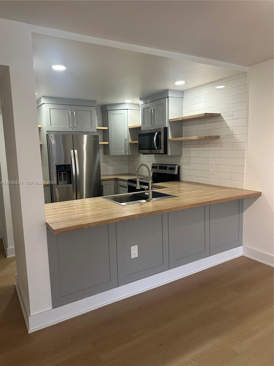 A kitchen features gray shaker cabinets, butcher block countertops, stainless steel appliances, and open shelving — 10425 SW 112th Ave # 215, Miami FL 33176, MIAMI, FL