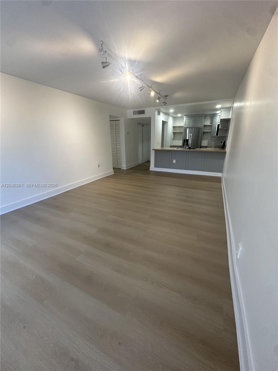 This open-concept living area features light wood-look flooring and a kitchen with gray cabinetry — 10425 SW 112th Ave # 215, Miami FL 33176, MIAMI, FL