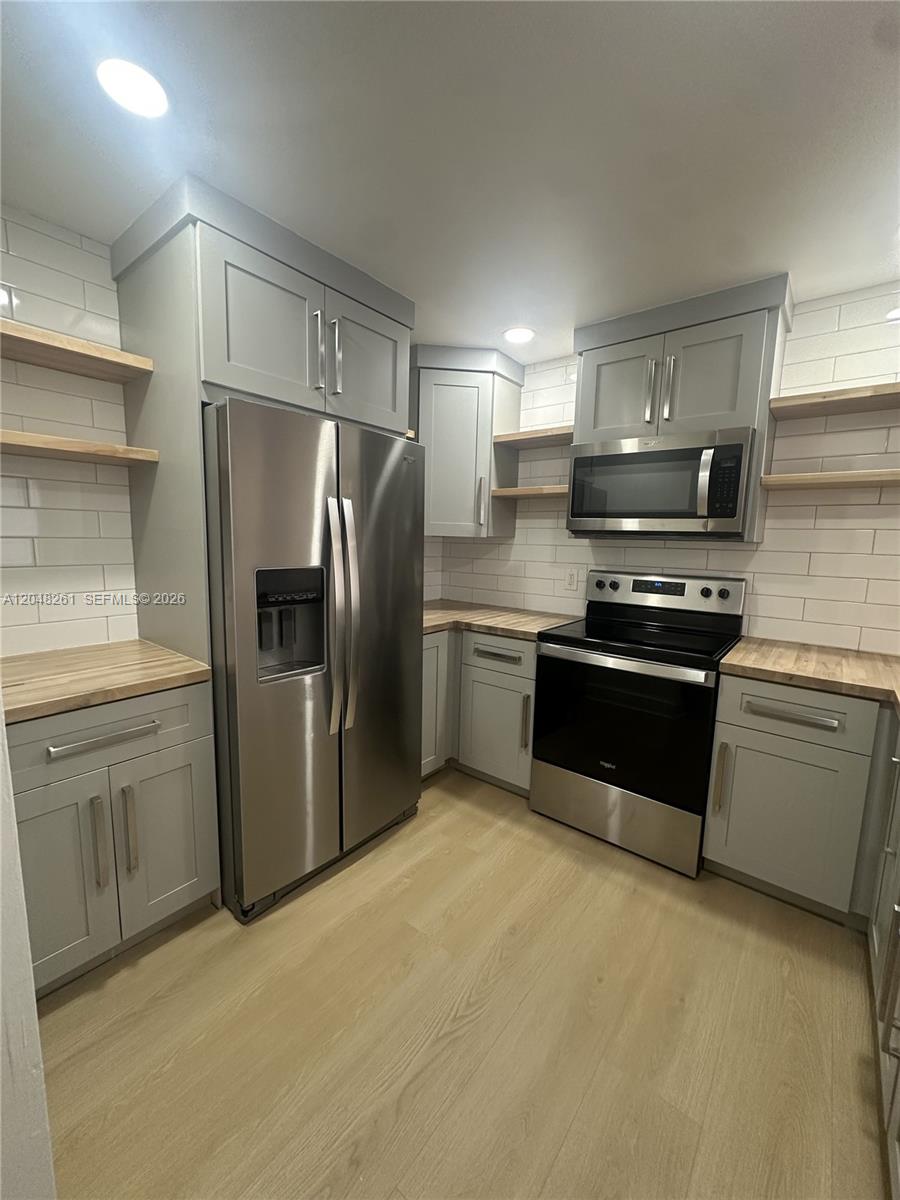 A kitchen features gray cabinets, stainless steel appliances, wood countertops, and white subway tile backsplashes — 10425 SW 112th Ave # 215, Miami FL 33176, MIAMI, FL