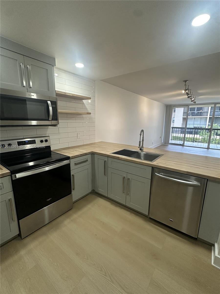 A kitchen features light gray cabinets, wood countertops, stainless steel appliances, and white subway tile — 10425 SW 112th Ave # 215, Miami FL 33176, MIAMI, FL