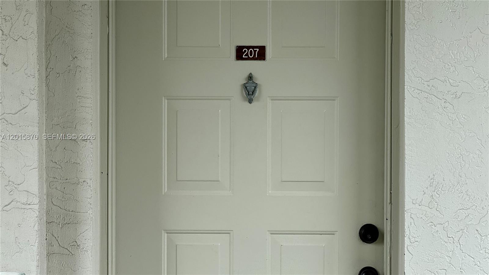 A light-colored front door features a silver knocker and the number 207 — 2236 N Cypress Bend Dr # 207, Pompano Beach FL 33069, POMPANO BEACH, FL