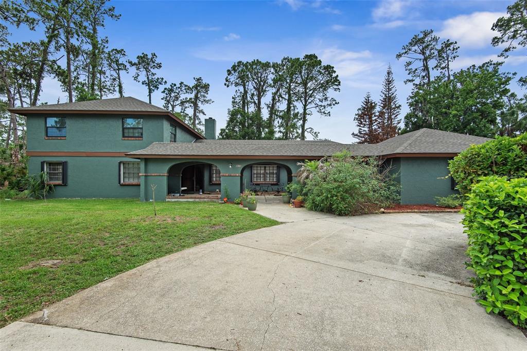 A two-story green house with a concrete driveway and a covered front porch — 326 WELLINGTON DRIVE, PALM COAST, FL