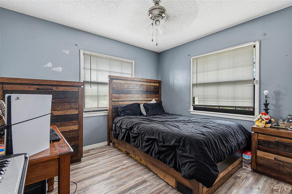 A bedroom features a wooden bed frame, a desk with a gaming console, and two windows — 326 WELLINGTON DRIVE, PALM COAST, FL