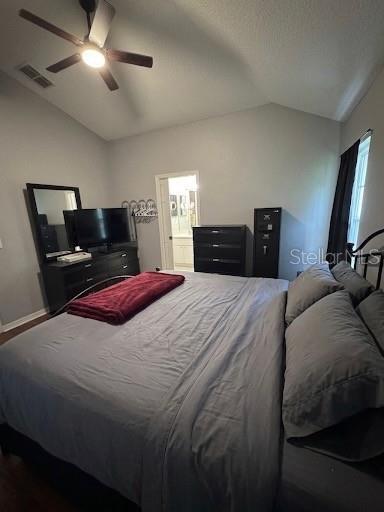 A bedroom features a large bed with grey bedding, a dark dresser, and a ceiling fan — 28511 SEASHELL COURT, WESLEY CHAPEL, FL