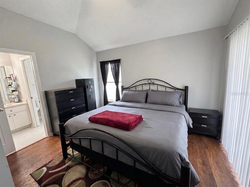 A bedroom features a metal bed frame, dark furniture, wood flooring, and an attached bathroom — 28511 SEASHELL COURT, WESLEY CHAPEL, FL