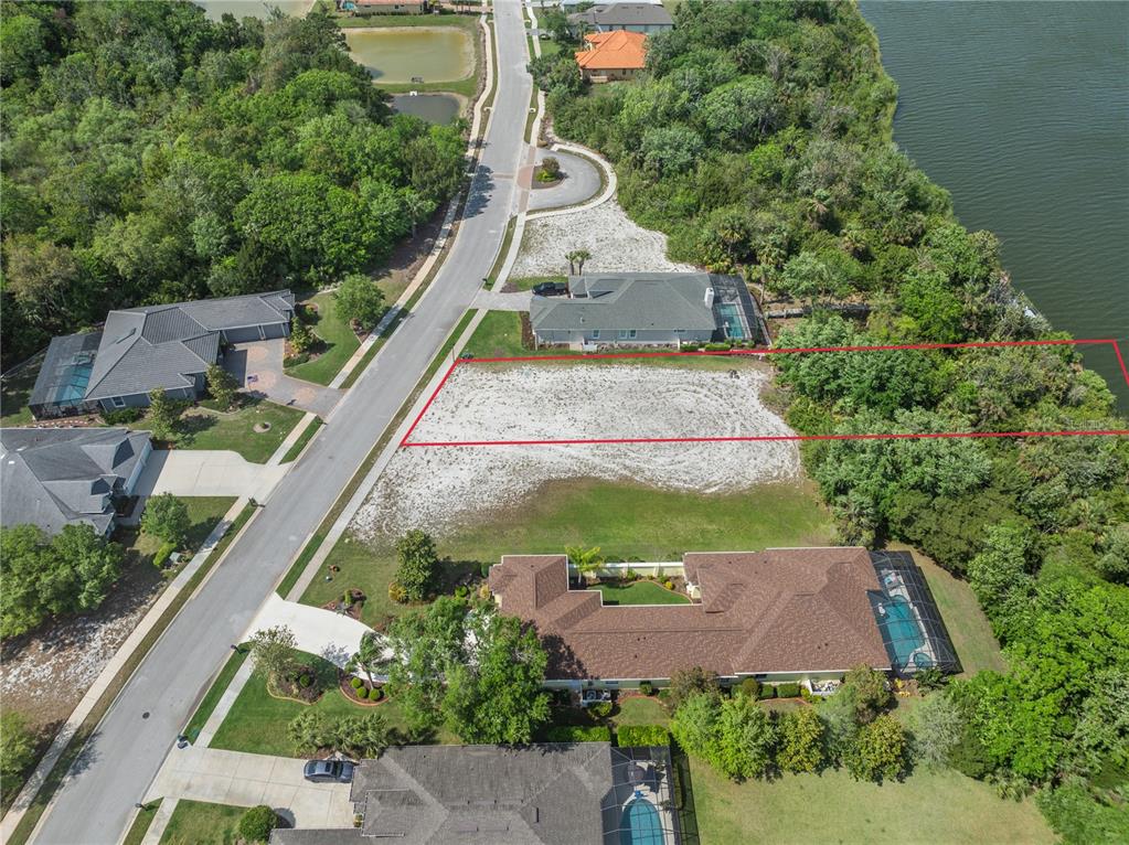 An aerial view shows a vacant residential lot outlined in red situated between two houses — 48 N LAKEWALK DRIVE, PALM COAST, FL